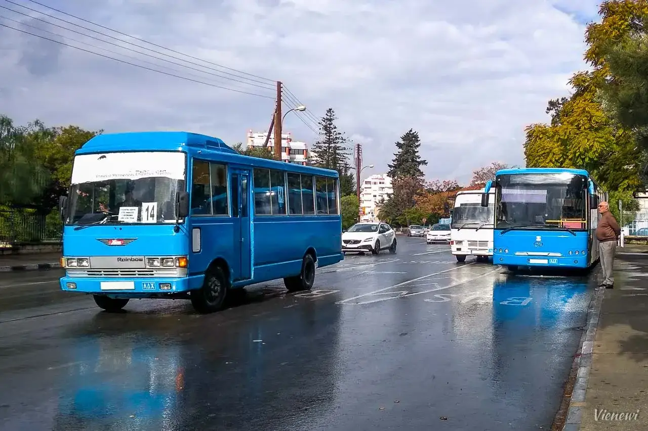 Nawierzchnia drogi na Cyprze jest mokra, a niebieski autobus z numerem 14 czeka na pasażerów. Komunikacja miejska na wyspie działa sprawnie.