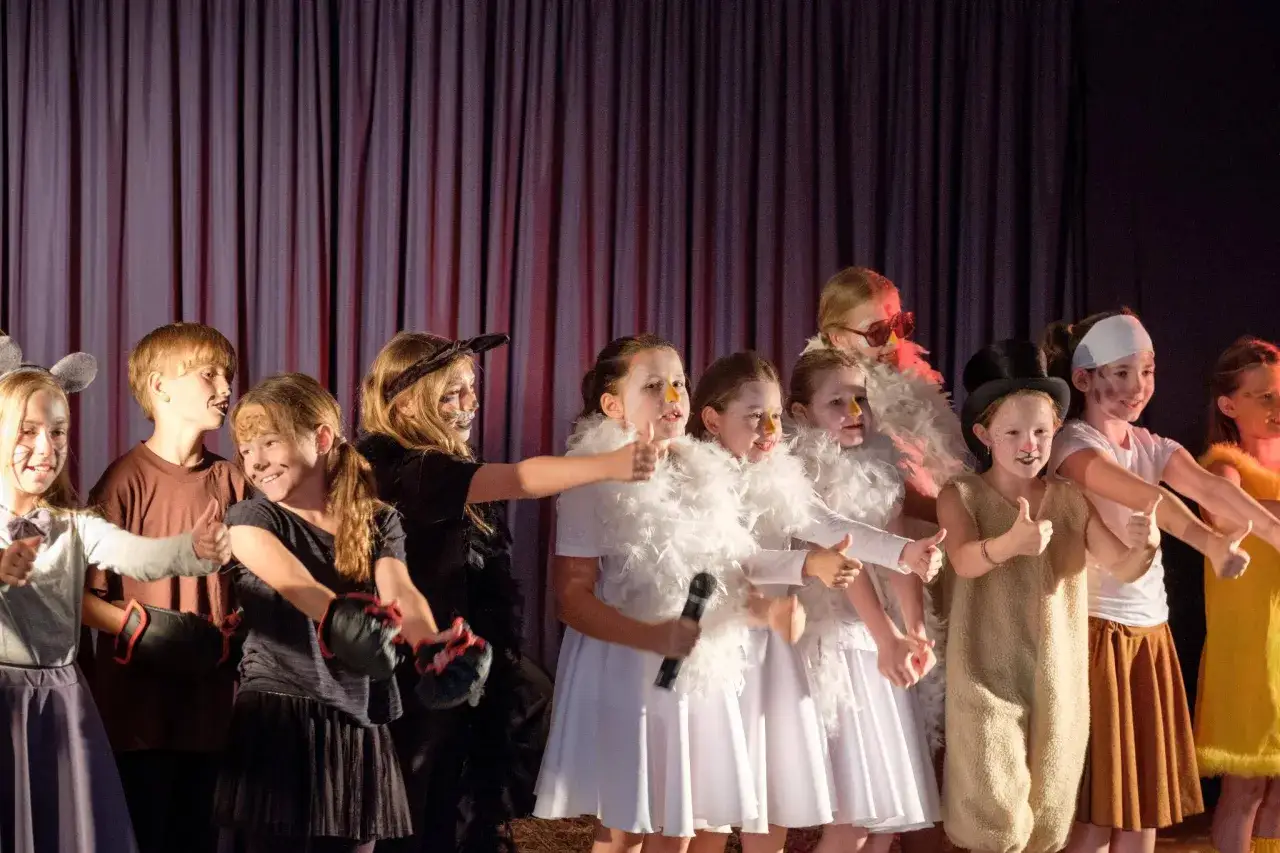 Kinder geben Daumen hoch bei einem Vorlesetheater in der Grundschule. Sie tragen Kostüme und sind geschminkt.