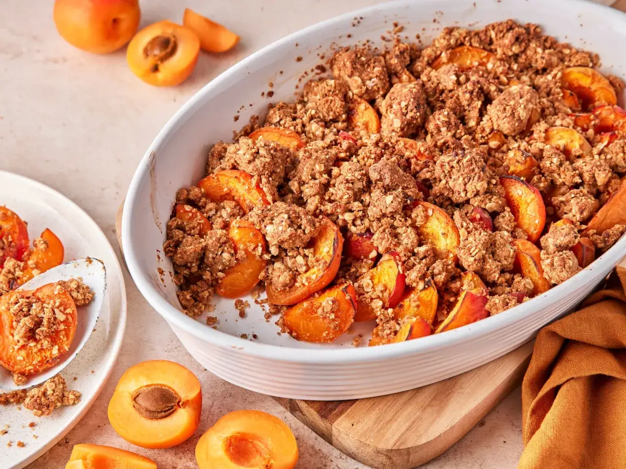 Saftiger Aprikosen Crumble in einer Auflaufform, mit frischen Aprikosen garniert. Ein Genuss!