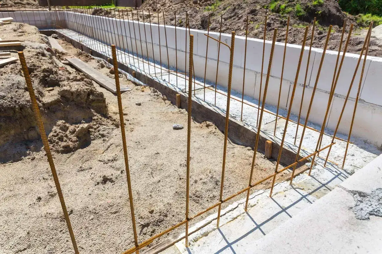 Zbrojenie fundamentów budowy, pionowe i poziome pręty stalowe tworzą siatkę wzmacniającą beton.