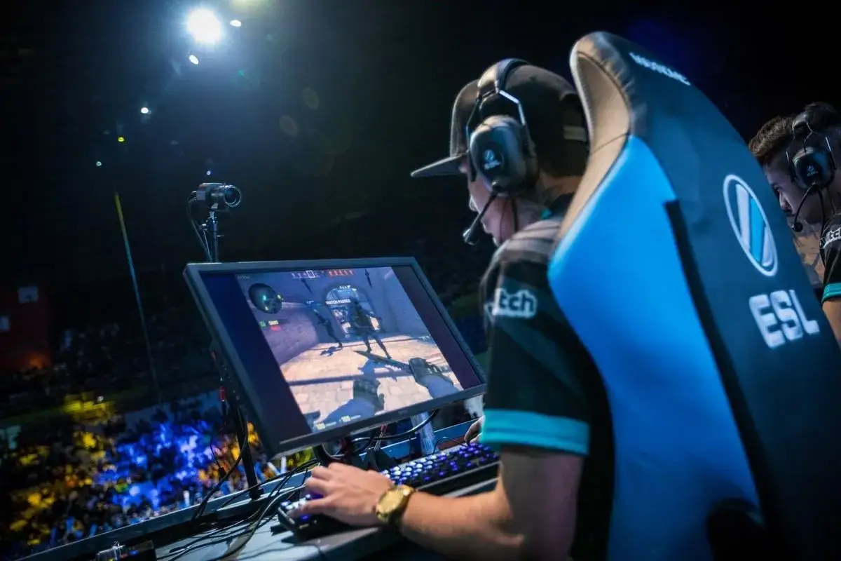 Gracz ESL w akcji, pokazujący, ile zarabiają pro gamerzy. W tle publiczność i światła sceny.