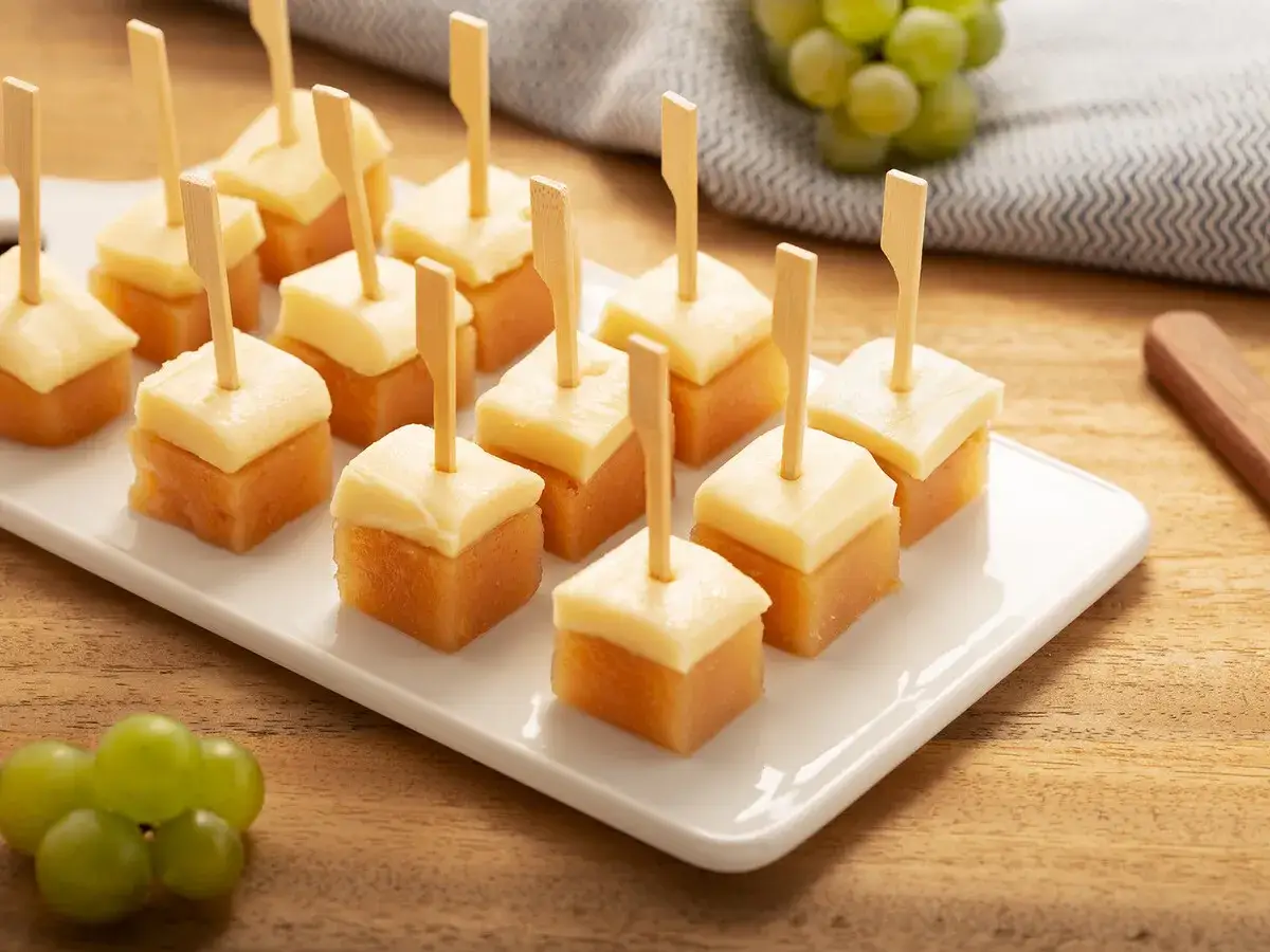 Bocaditos de queso y dulce de **carne de membrillo** servidos en una bandeja blanca, listos para disfrutar.