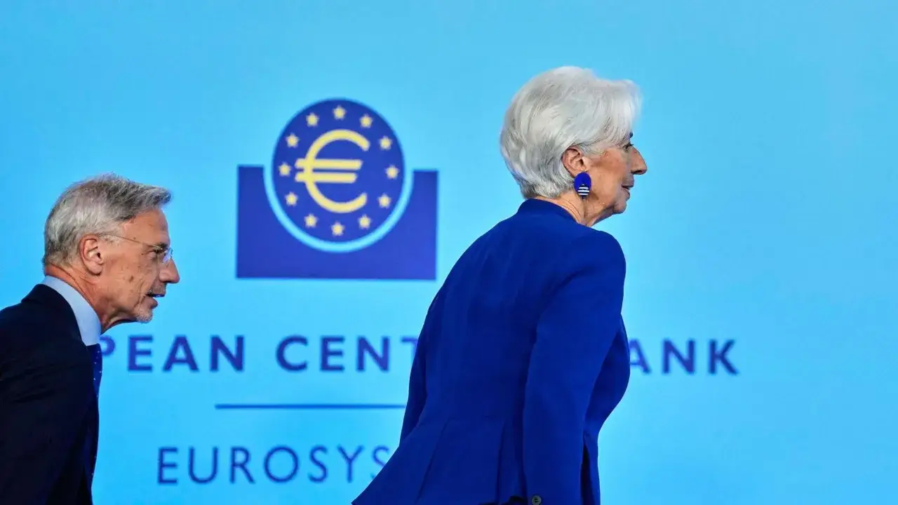 Zwei EZB-Ratsmitglieder, Christine Lagarde und ein Mann, gehen vor dem Logo der Europäischen Zentralbank.