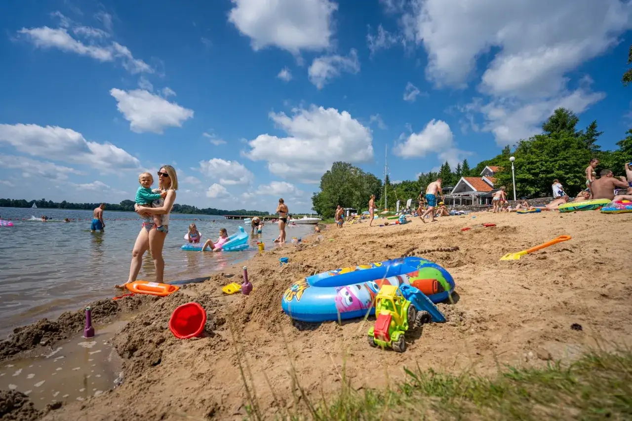 Rodzina cieszy się słońcem i zabawą na plaży. Idealne miejsce, gdzie na Mazury z dziećmi.