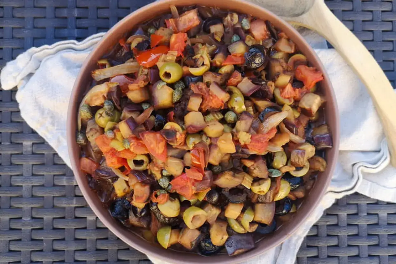 Un plat color&eacute; de caponata sicilienne, m&eacute;lange d'aubergines, tomates, olives et c&acirc;pres, pr&ecirc;t &agrave; &ecirc;tre d&eacute;gust&eacute;.