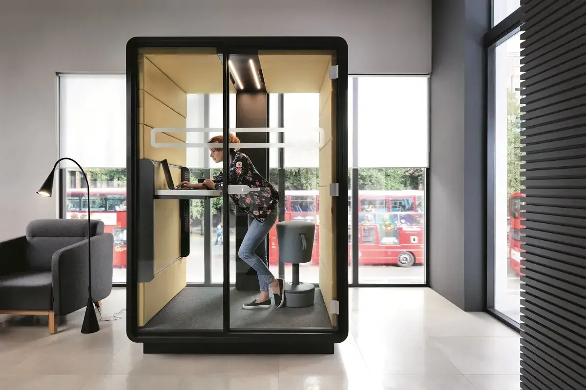 Una donna lavora in una cabina insonorizzata, un ambiente che favorisce la concentrazione per chiunque, inclusi coloro con autismo, promuovendo un'inclusione lavorativa.
