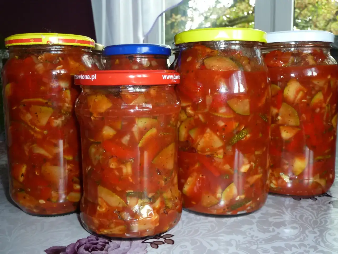 Słoiki pełne domowego **ketchupu z cukinii**, gotowe na zimę. Aromatyczne warzywa w sosie pomidorowym.