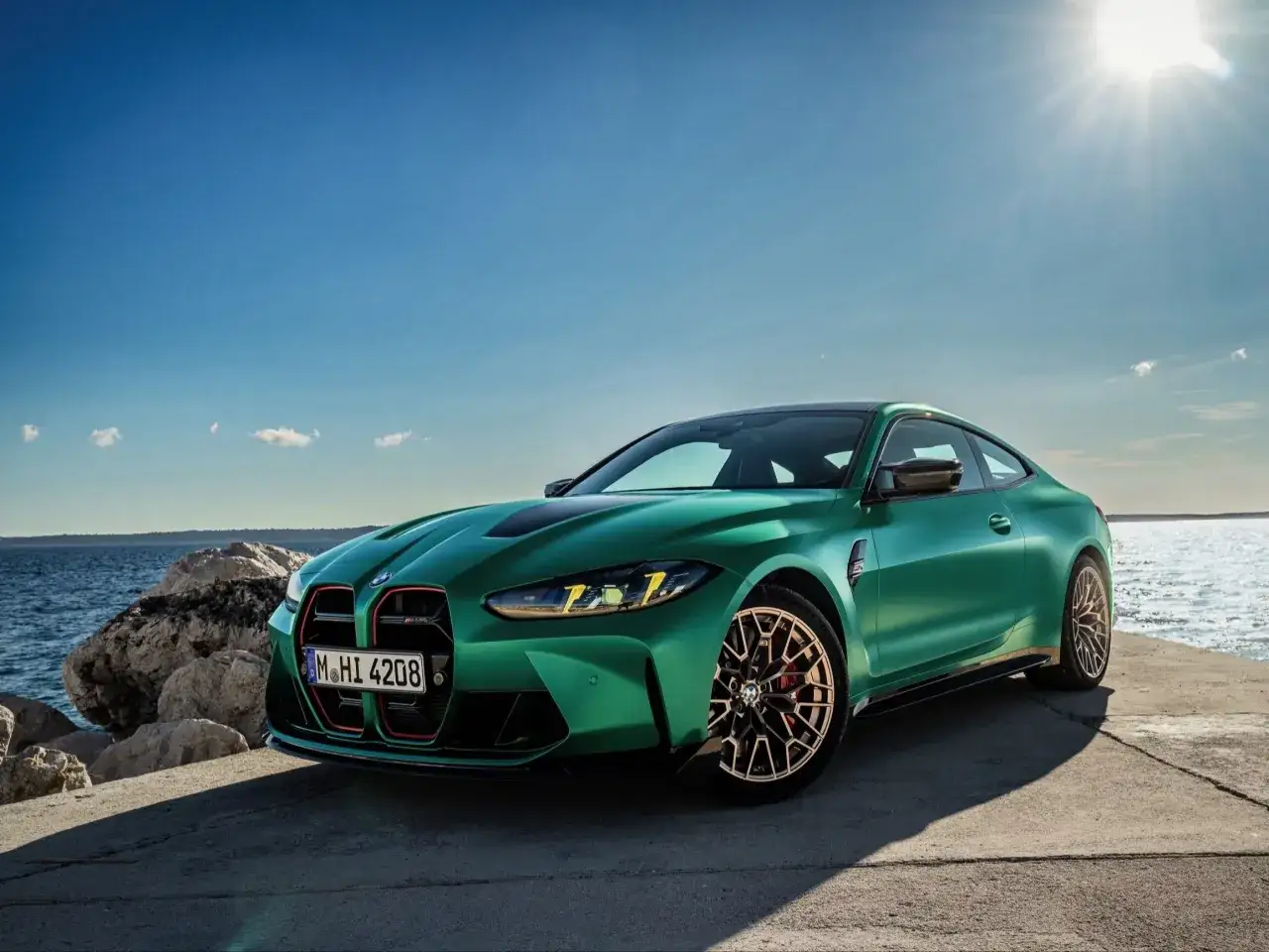 Zielony BMW M4 CS błyszczy na tle błękitnego nieba i morza.