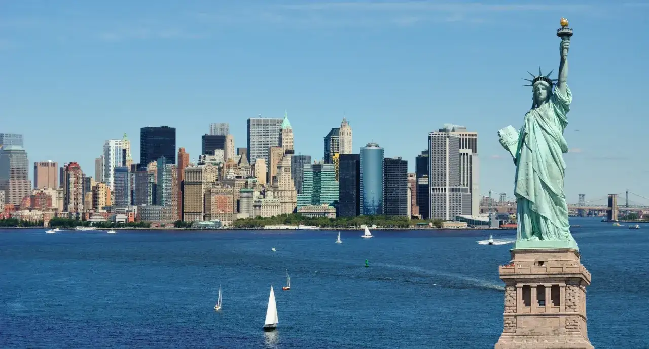 Statua Wolności i panorama Manhattanu, klasyczne **nowy jork atrakcje**. W tle żaglówki i mosty.