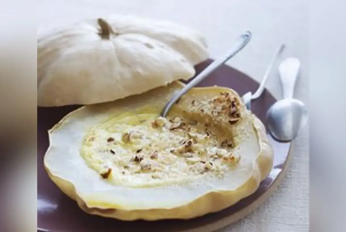 Patisson farci, une recette gourmande. Ce légume d'été est garni d'une préparation crémeuse et de noix, prêt à être dégusté.