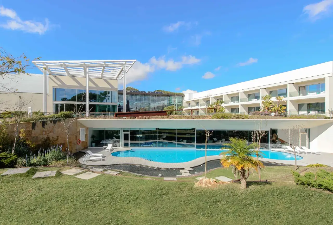 Modernes Hotel mit Pool und Liegen, umgeben von Grünflächen. Ein perfekter Ort für einen entspannten Urlaub in Cascais bei Lissabon.