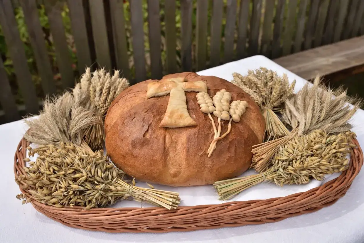 Chleb dożynkowy ozdobiony krzyżem i kłosami. Inspiracja, jak ozdobić chleb dożynkowy, by wyglądał pięknie.