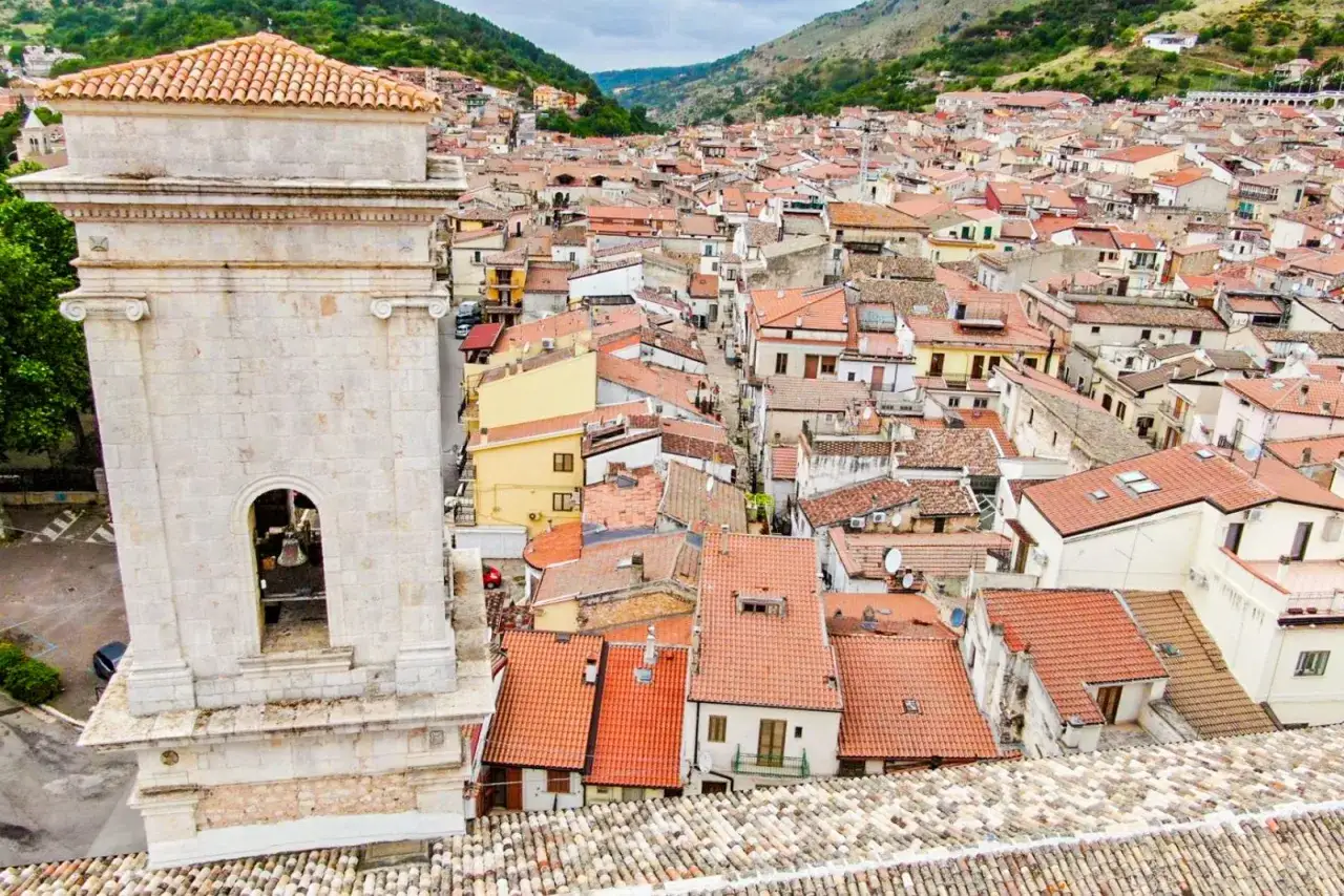 Vista dall'alto di San Marco in Lamis: un campanile in pietra domina un dedalo di tetti rossi e case aggrappate alla collina. Cosa vedere in questo borgo?