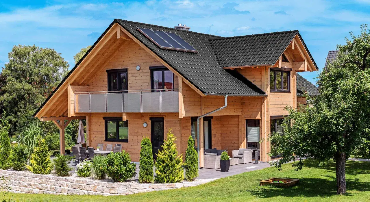 Holzhaus mit Solaranlage auf dem Dach, Balkon und Terrasse. Ein idyllisches **cabin house** im Grünen.