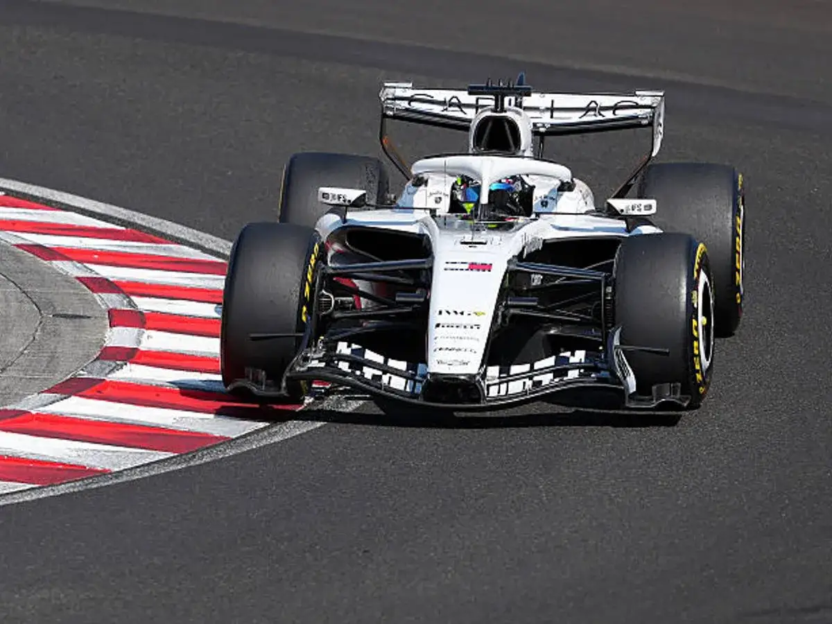 Un coche de sprint F1 blanco y negro toma una curva cerrada, con sus neum&aacute;ticos rozando la l&iacute;nea roja y blanca de la pista.