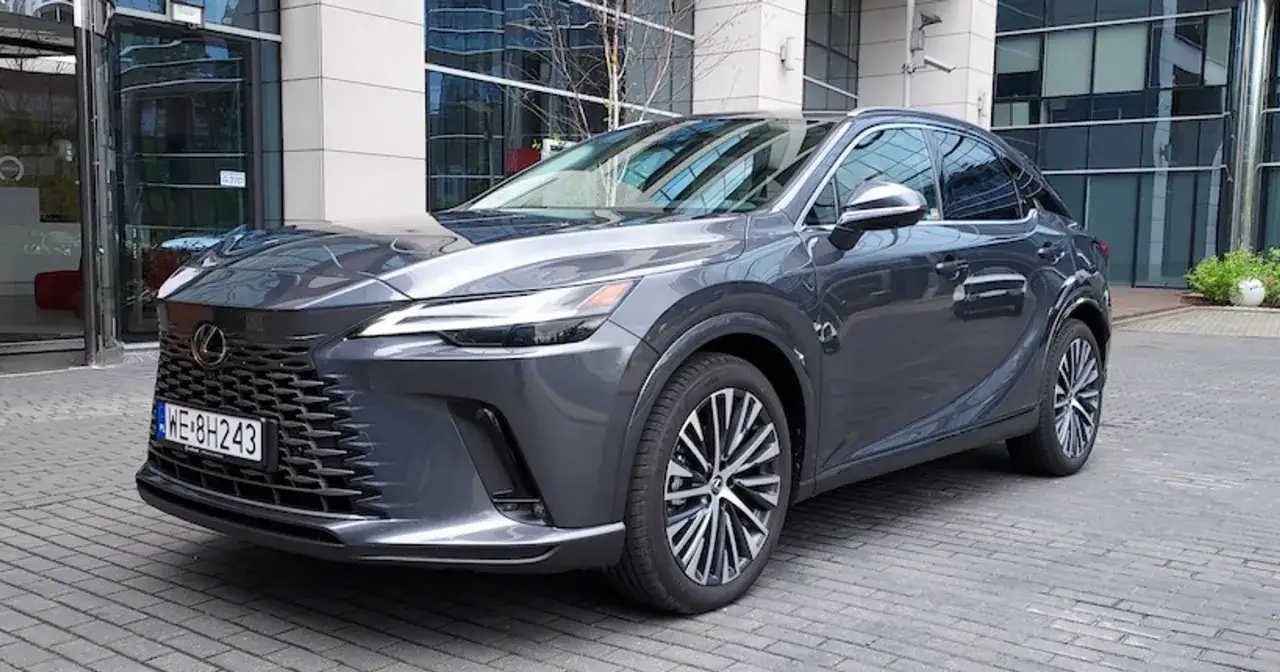 Elegancki, ciemnoszary Lexus RX 450h zaparkowany przed nowoczesnym budynkiem.