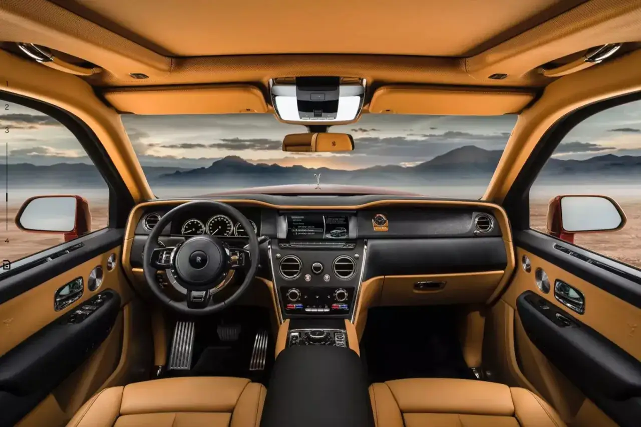 Wnętrze Rolls-Royce Cullinan z brązową skórzaną tapicerką i widokiem na góry.