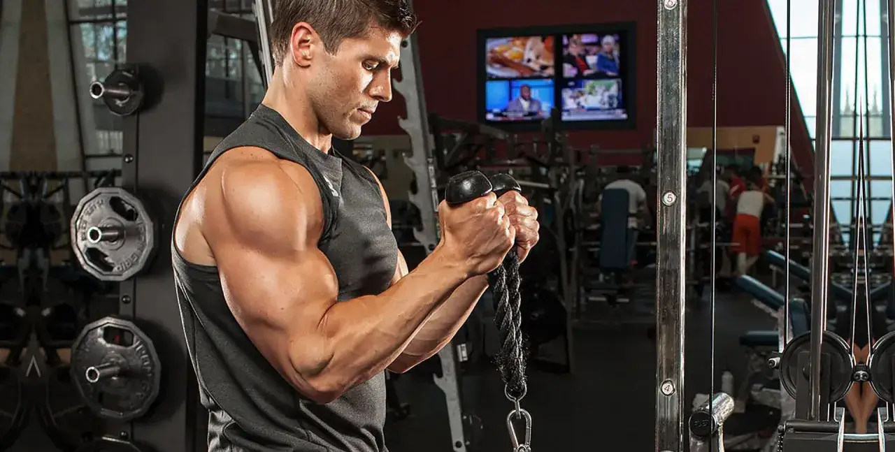 Man utf&ouml;r cable biceps curl med rep i ett gym.