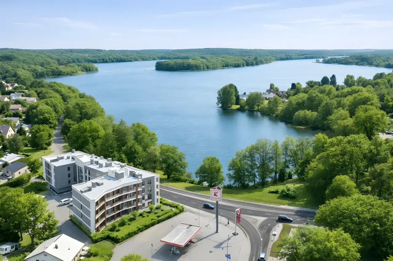 Nowoczesne osiedle panorama park nad jeziorem, otoczone zielenią. Widok z lotu ptaka na budynki mieszkalne, drogę i rozległy akwen wodny.
