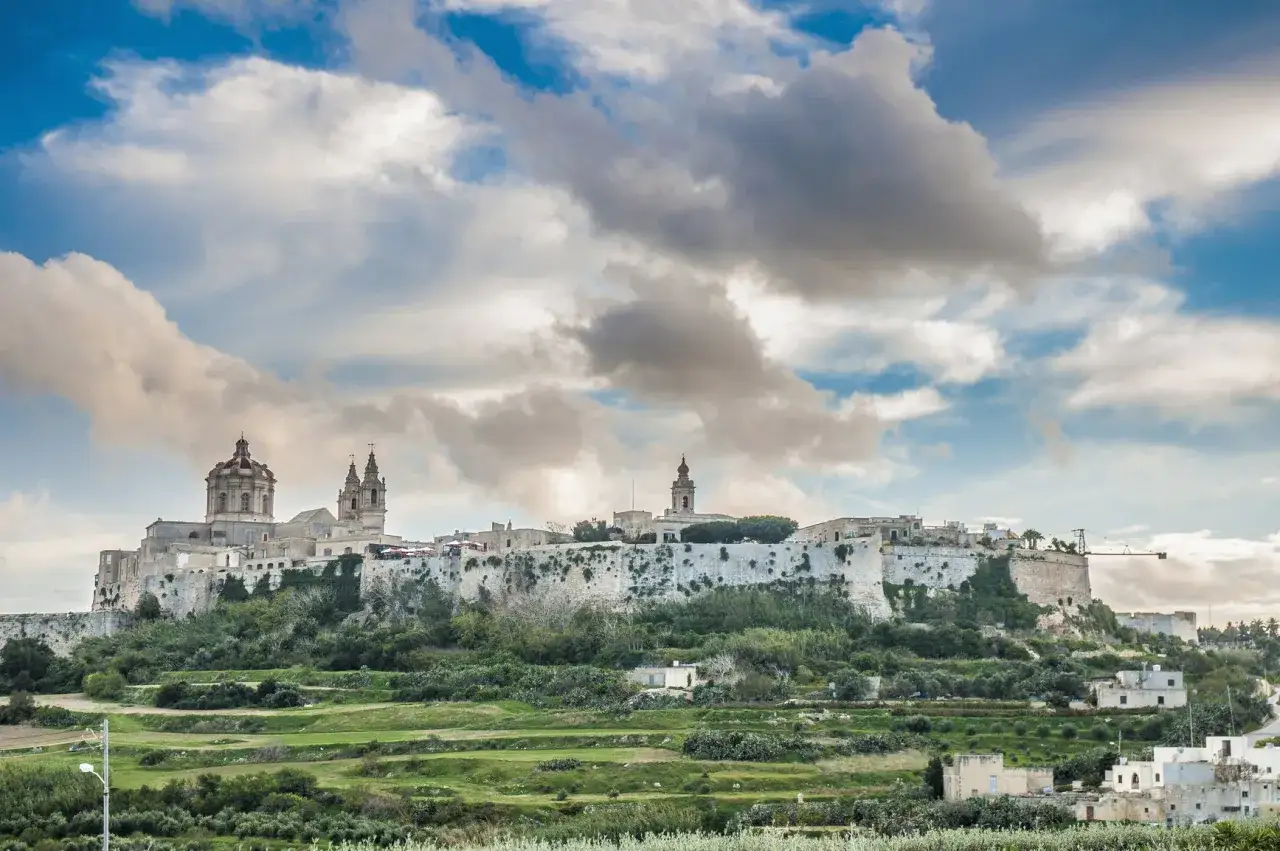 Mdina Malta, dawna stolica, wznosi się na wzgórzu, otoczona murami obronnymi. Widoczne kopuły i wieże katedry.