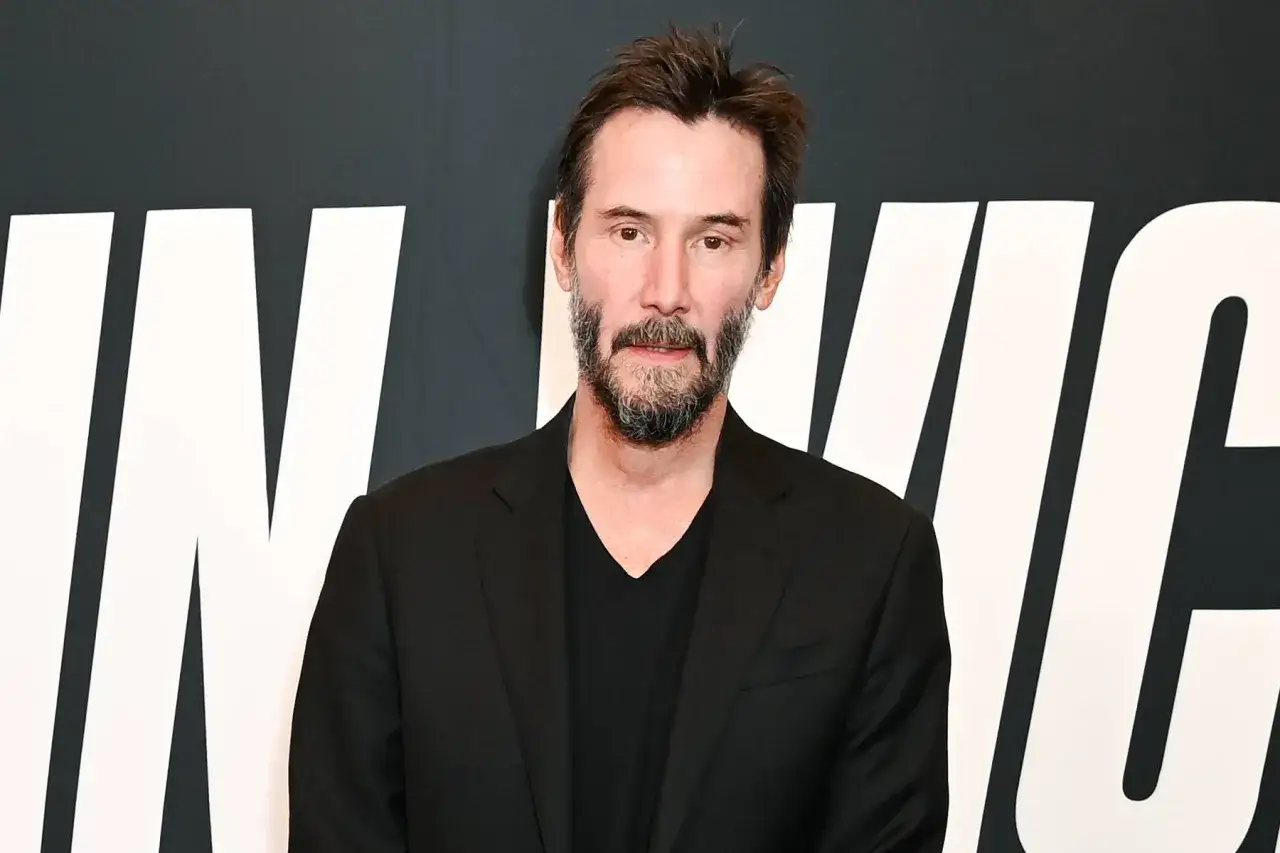 Keanu Reeves, bereit f&uuml;r John Wick 5, tr&auml;gt einen schwarzen Anzug und ein schwarzes Hemd.