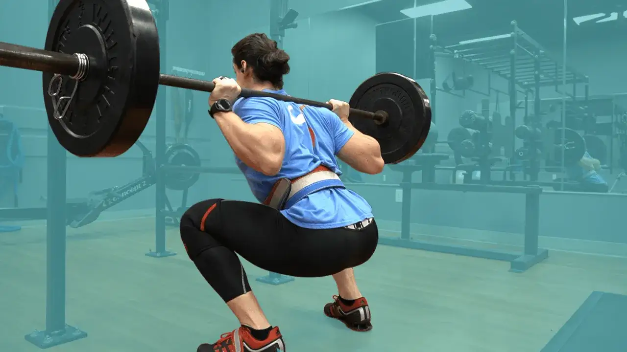 Person macht Kniebeugen mit Langhantel f&uuml;r Muskelaufbau. Krafttraining im Fitnessstudio.