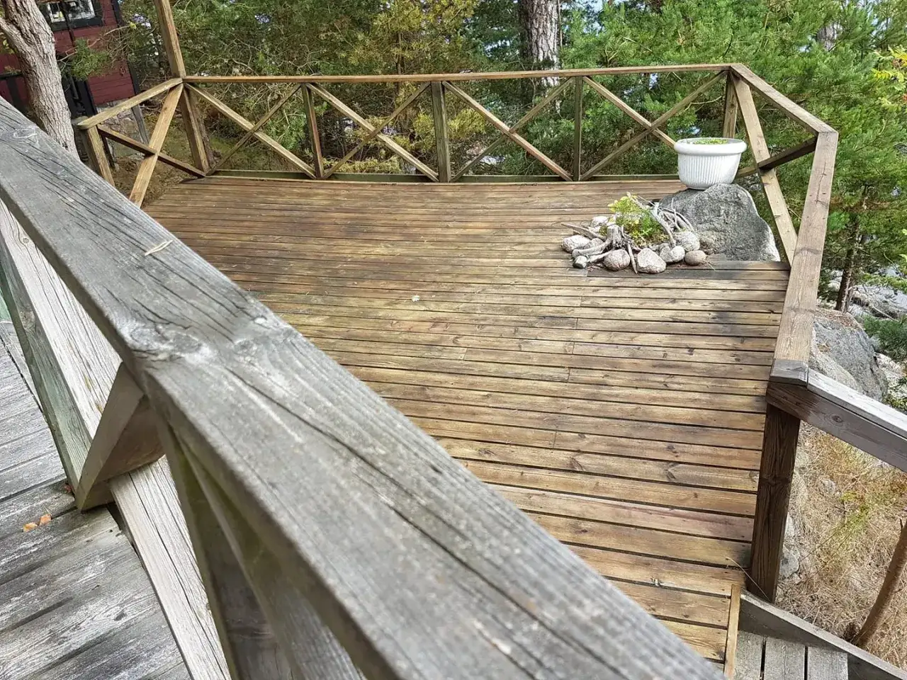 Trallen p&aring; altanen beh&ouml;ver m&aring;las. En vit kruka st&aring;r p&aring; en sten.
