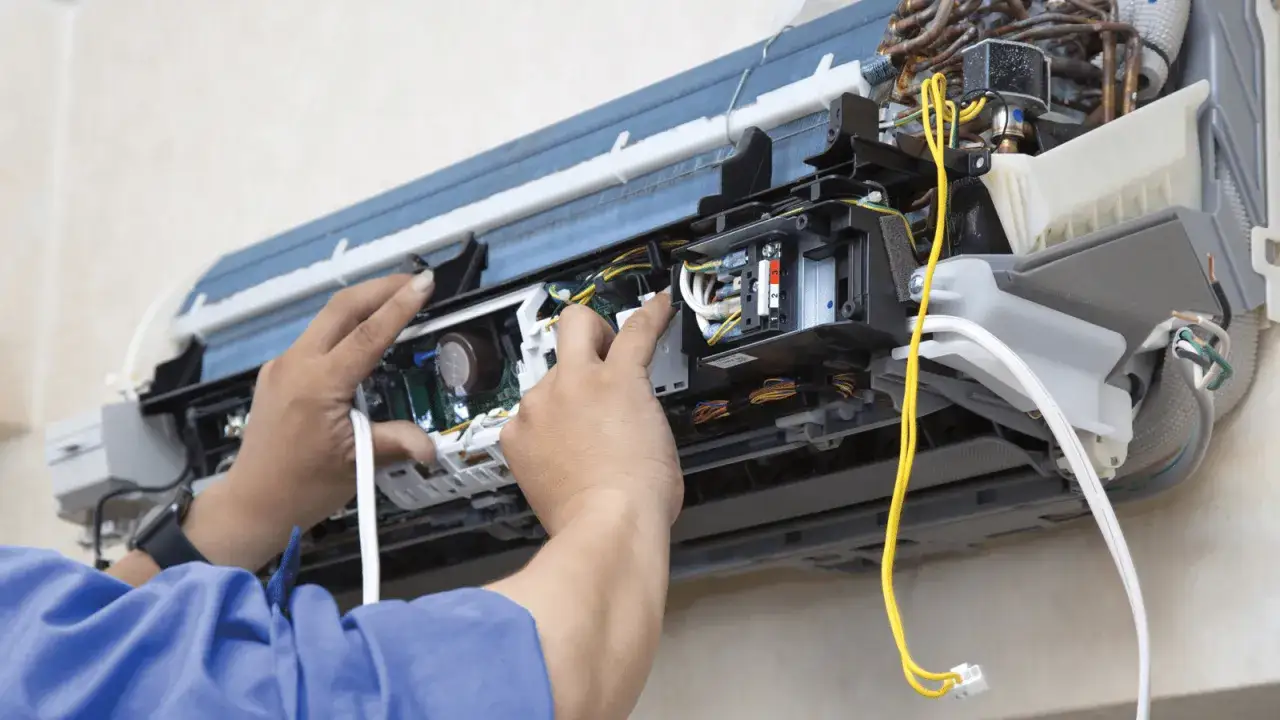 T&eacute;cnico trabajando en el interior de un aire acondicionado, posiblemente para cargar gas.