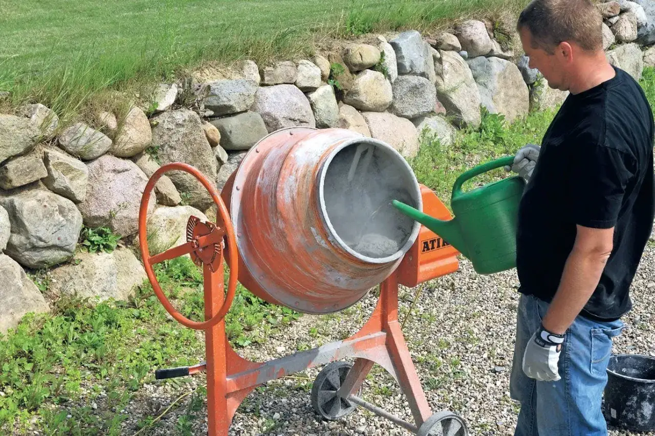 Man häller vatten i en betongblandare för att blanda betong.