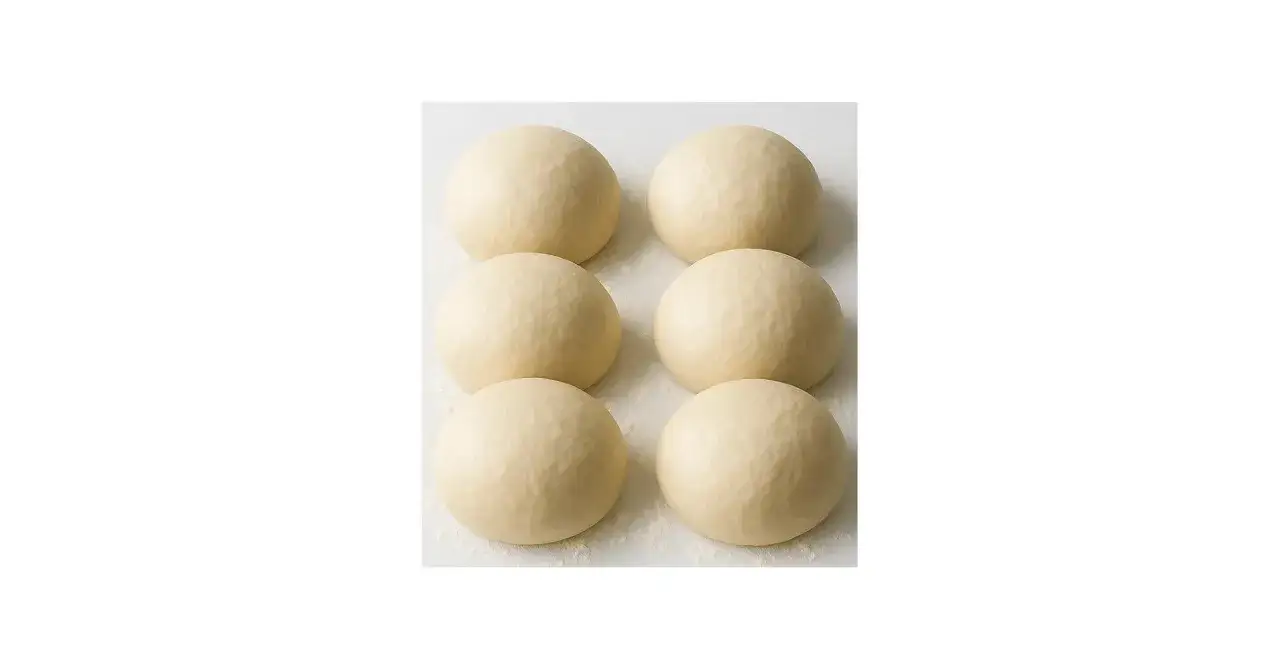 Sechs Kugeln Pizzateig, original Rezept von einem italienischen Gastronomen, liegen auf einer bemehlten Fläche.