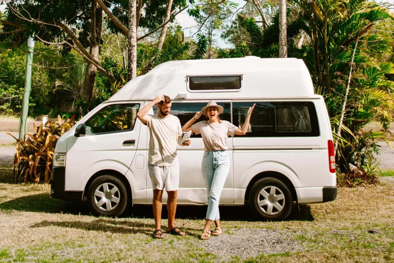 Ein Paar steht vor einem Campervan in Australien. Sie scheinen sich zu fragen, ob sich 2 Wochen Australien lohnen.