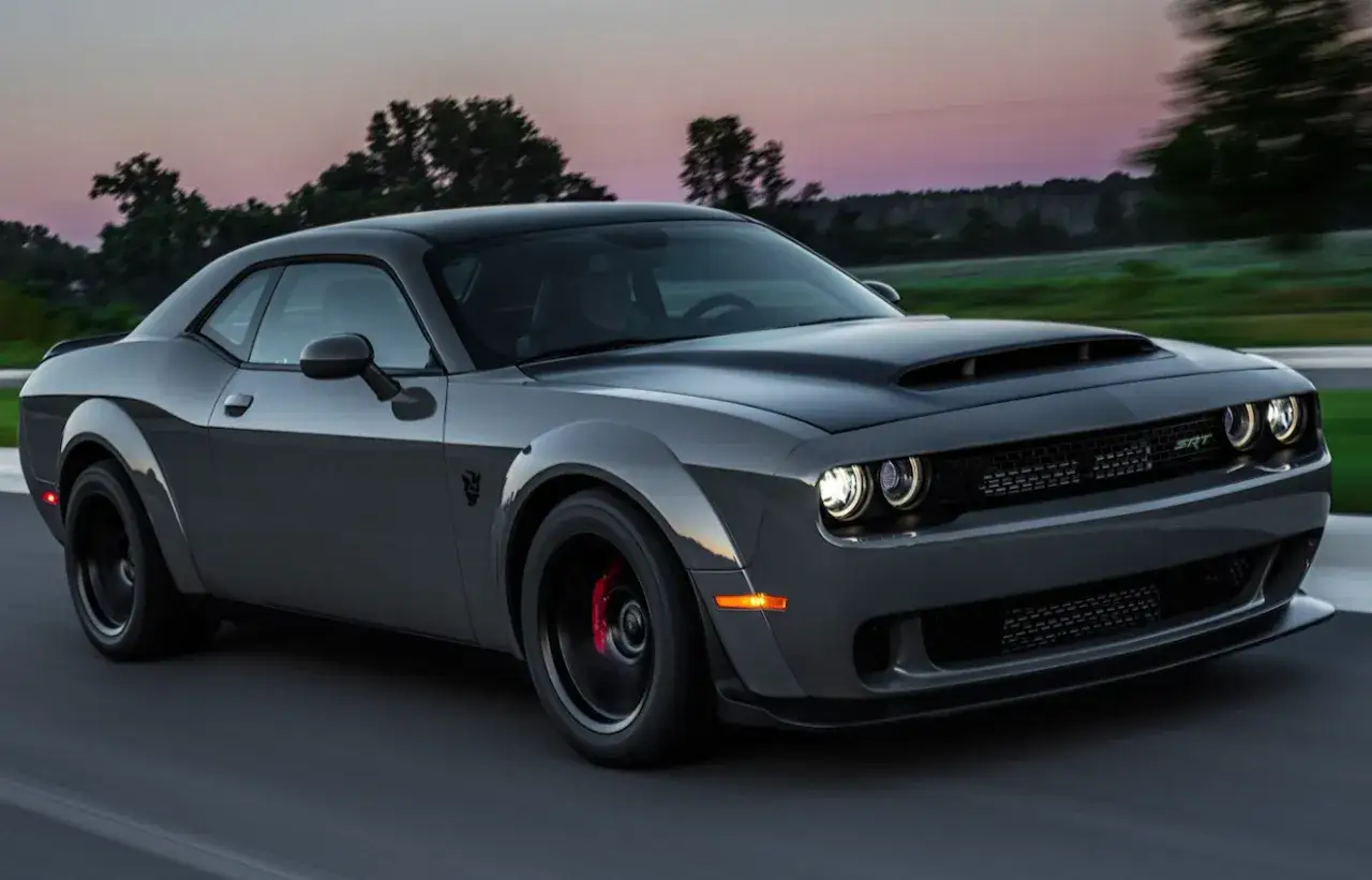 Szary Dodge Challenger SRT pędzi po drodze o zachodzie słońca. Sprawdź aktualną dodge challenger cena.