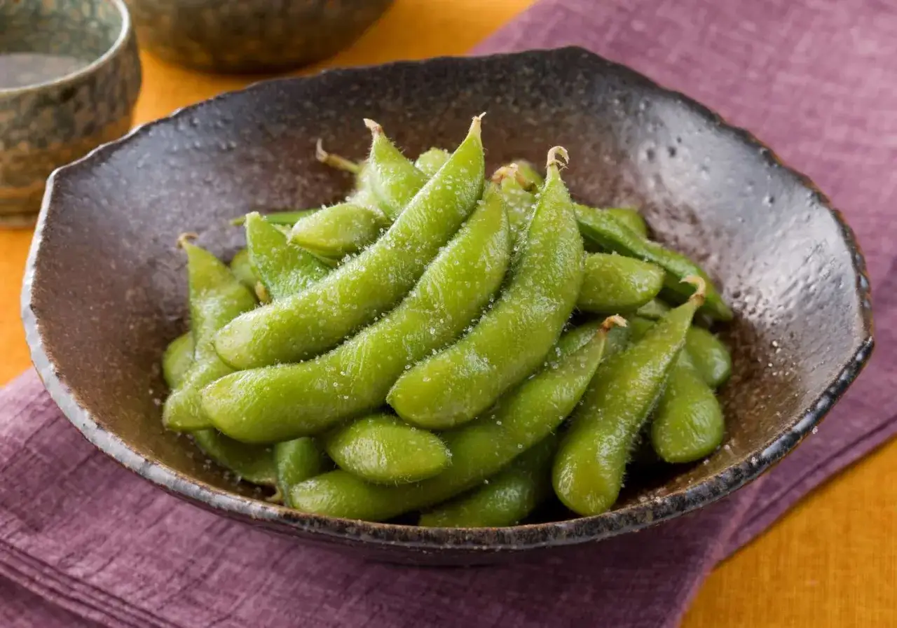 Zielone strączki soi posypane solą w misce. Edamame co to? To pyszna i zdrowa przekąska.