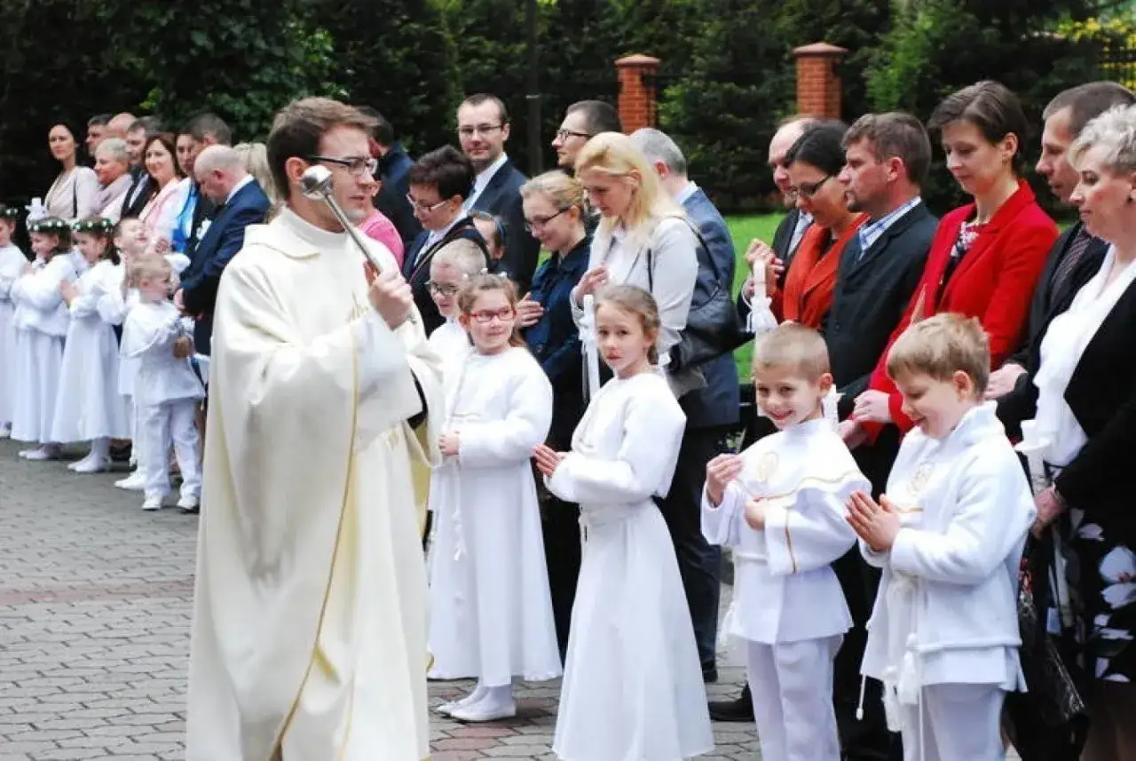 Ksiądz błogosławi dzieci do komunii. Rodzice zastanawiają się, ile dać księdzu na ślub, gdy widzą uroczystość.