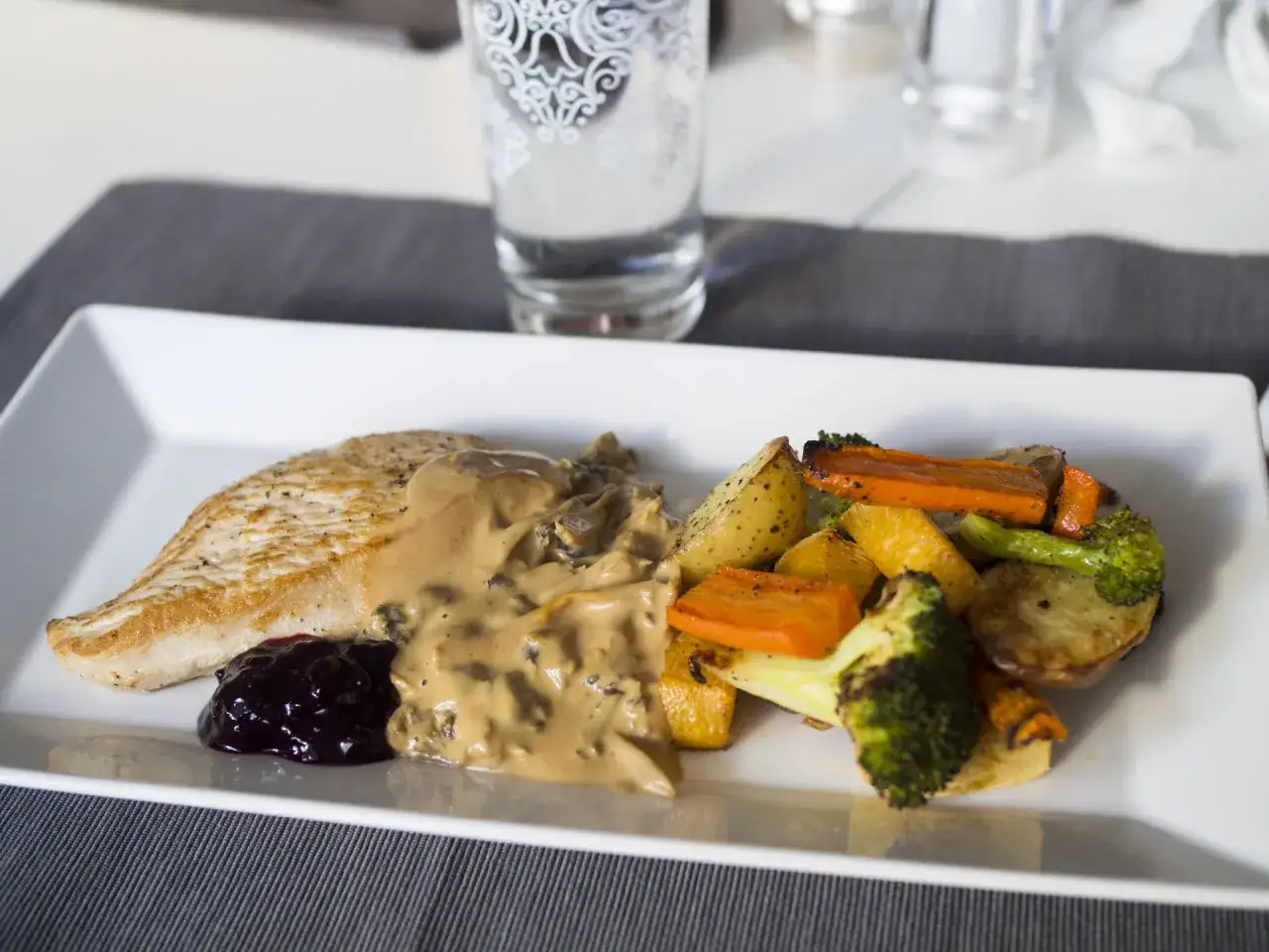 En tallrik med stekt kalkonfilé, krämig svampsås, lingonsylt och ugnsrostade rotfrukter. En perfekt måltid att koka kalkon till.