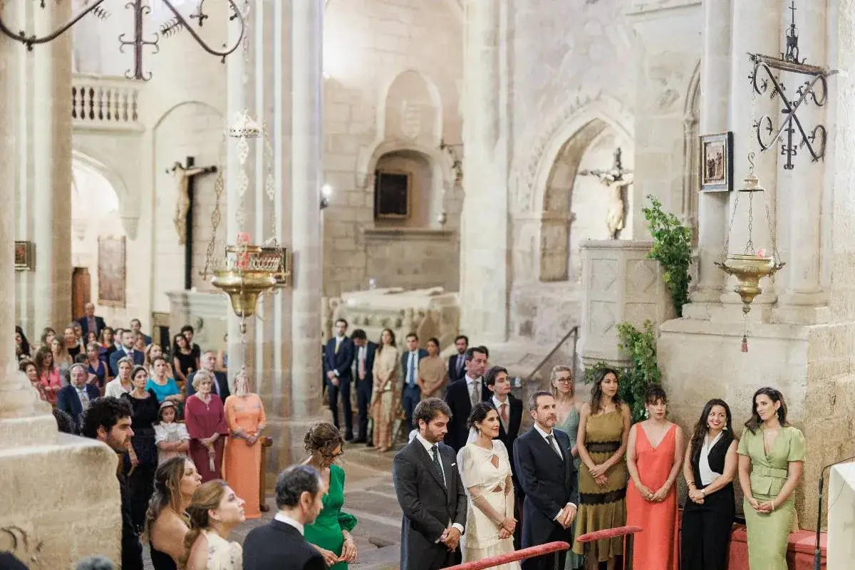 En una boda en una iglesia, se ve a los invitados y a la pareja. No se sabe como se llaman las damas de honor del novio.