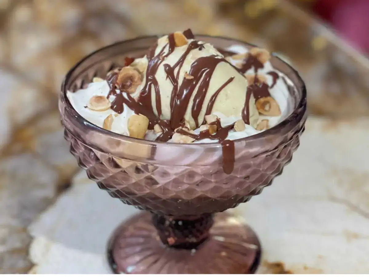 Une coupe de glace &agrave; la vanille, napp&eacute;e de sauce au chocolat et parsem&eacute;e de noisettes concass&eacute;es. Un d&eacute;lice gourmand !