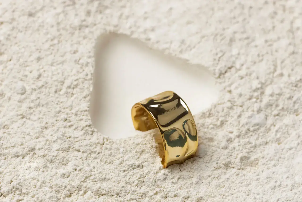 Un anello in oro 375, che corrisponde a 9 carati, giace su una polvere bianca.
