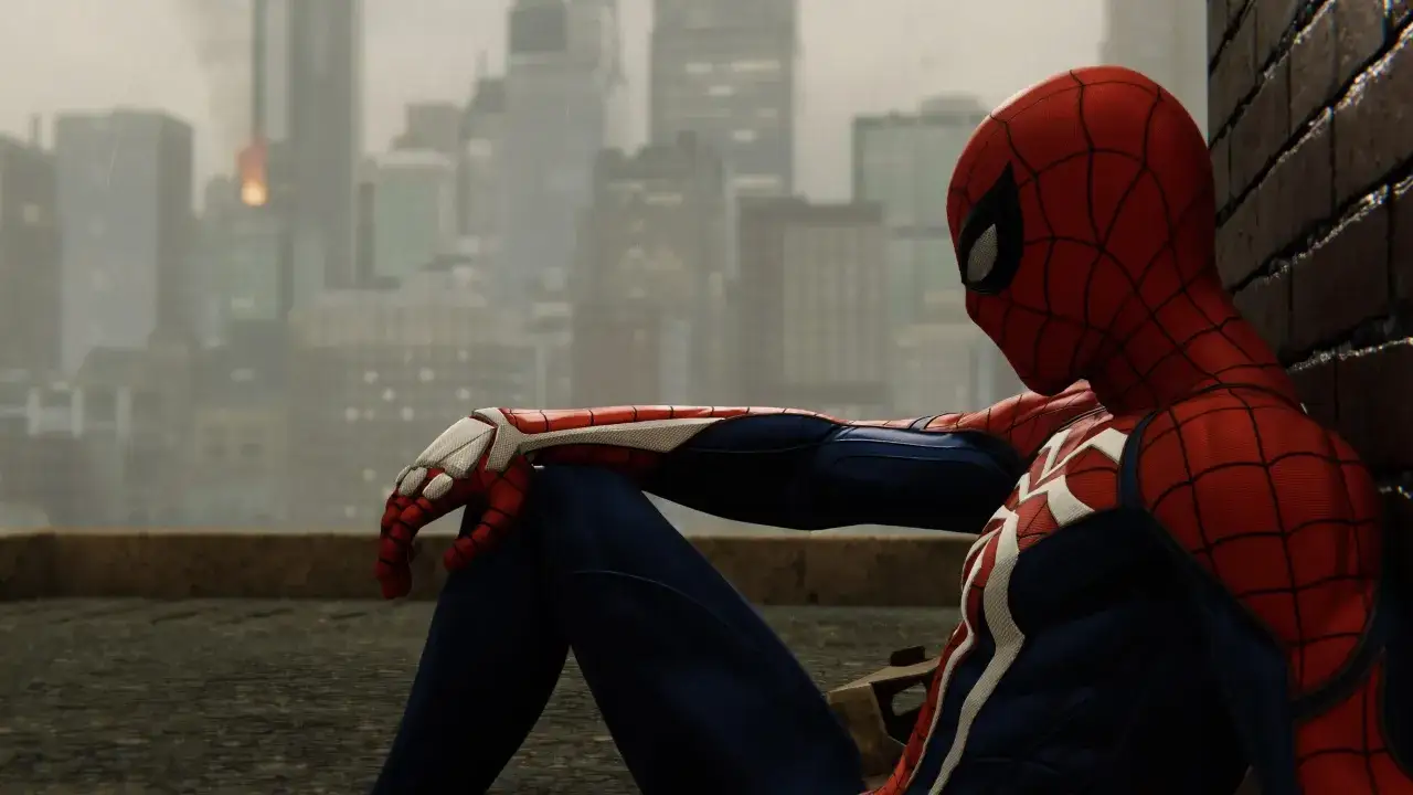 Spider-Man, agotado tras un día de lucha, descansa en un tejado. La ciudad lluviosa de fondo evoca la atmósfera de los juegos de Spider-Man.