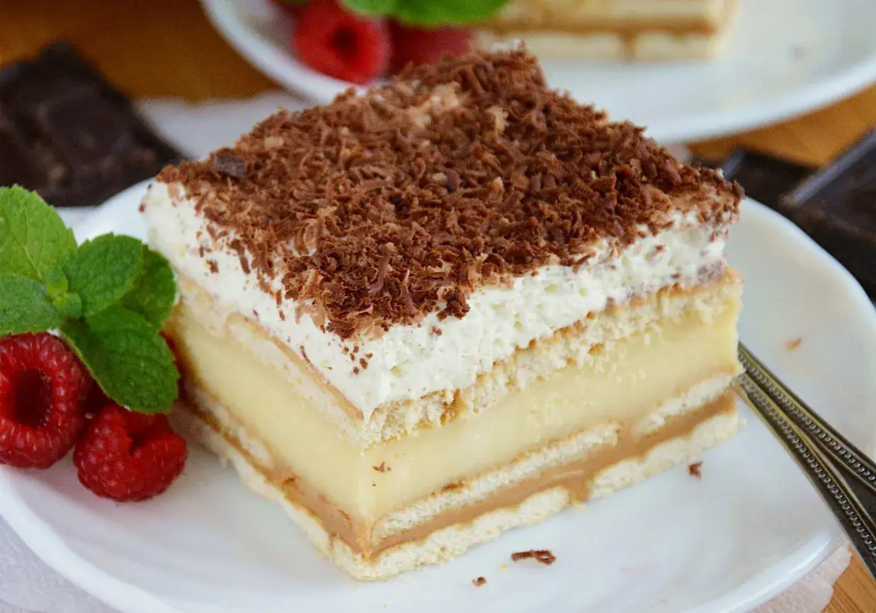 Pyszne ciasto 3 bit, prosty przepis. Warstwy biszkoptu, kremu budyniowego i kajmaku, zwieńczone bitą śmietaną i czekoladą.
