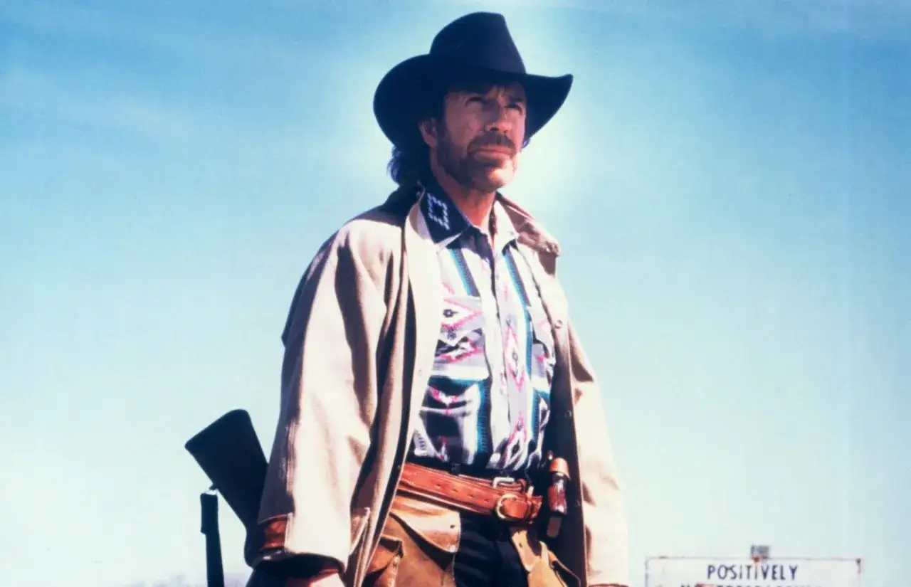 Chuck Norris, strażnik Teksasu, w kapeluszu i z karabinem, gotowy do akcji.
