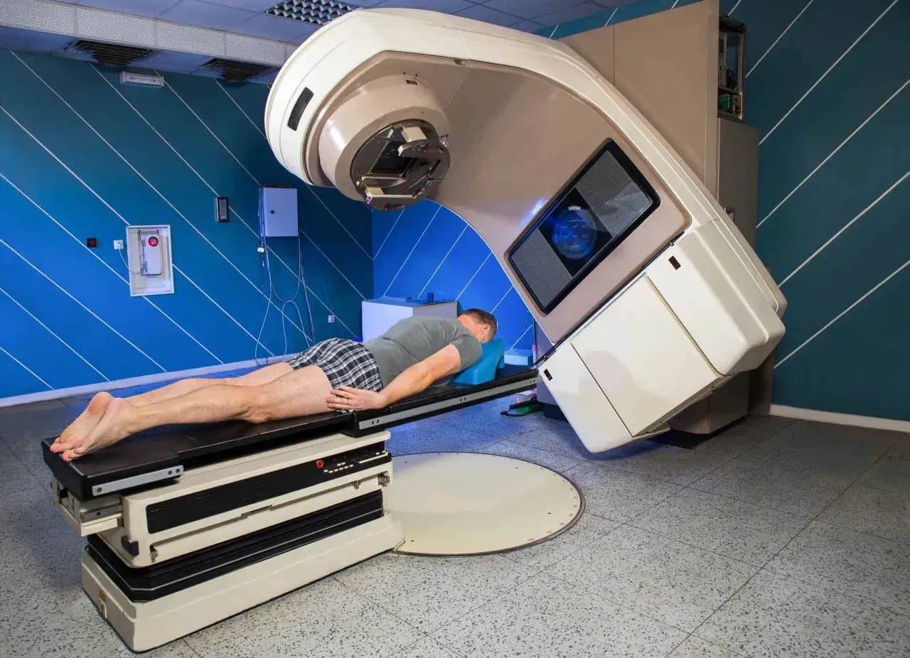 Mann liegt auf Liege unter Bestrahlungsger&auml;t. Hoffnung auf l&auml;ngere Lebenserwartung bei Lungenkrebs durch Strahlentherapie.