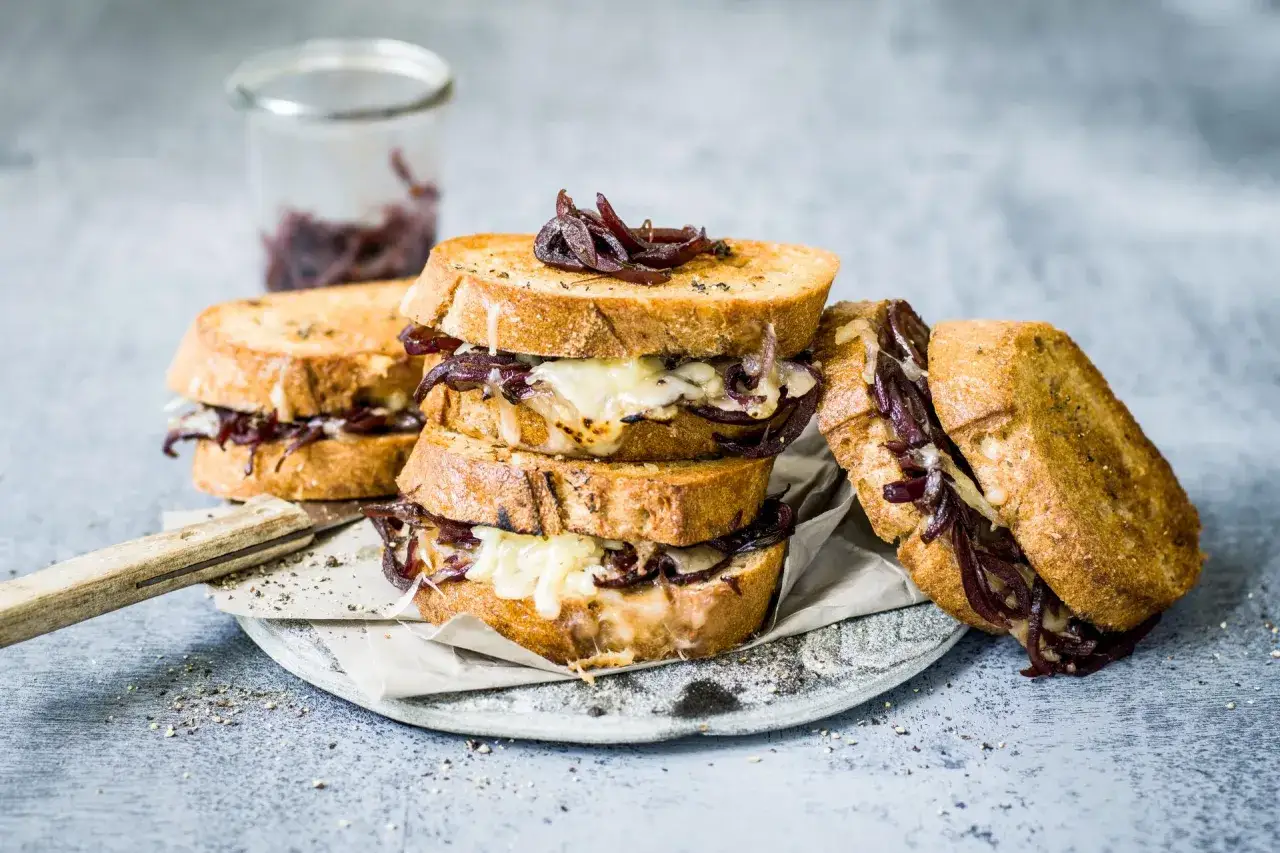 Un d&eacute;licieux croque montagnard, empil&eacute; avec du fromage fondant et des oignons caram&eacute;lis&eacute;s, pr&ecirc;t &agrave; &ecirc;tre d&eacute;gust&eacute;.