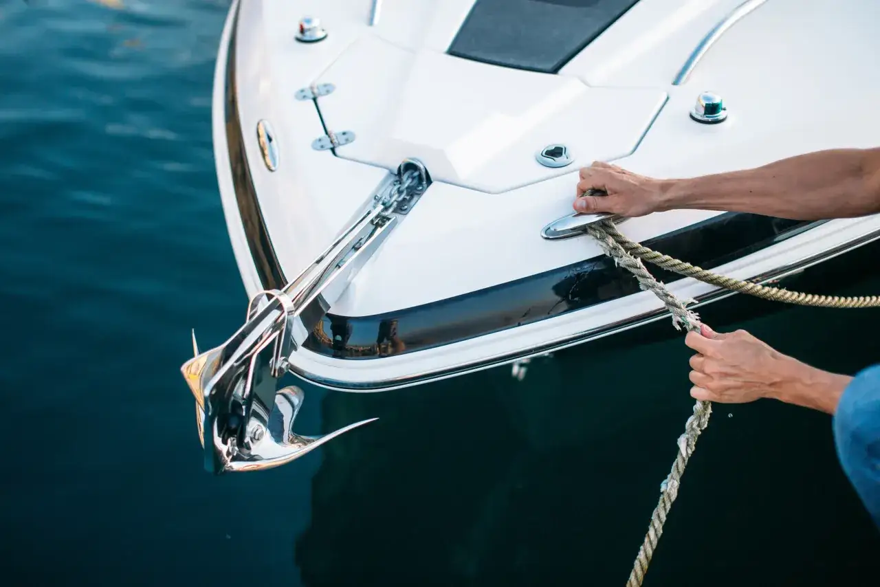 Main d'un homme tenant une corde pour attacher un bateau, un nœud marin facile à réaliser.