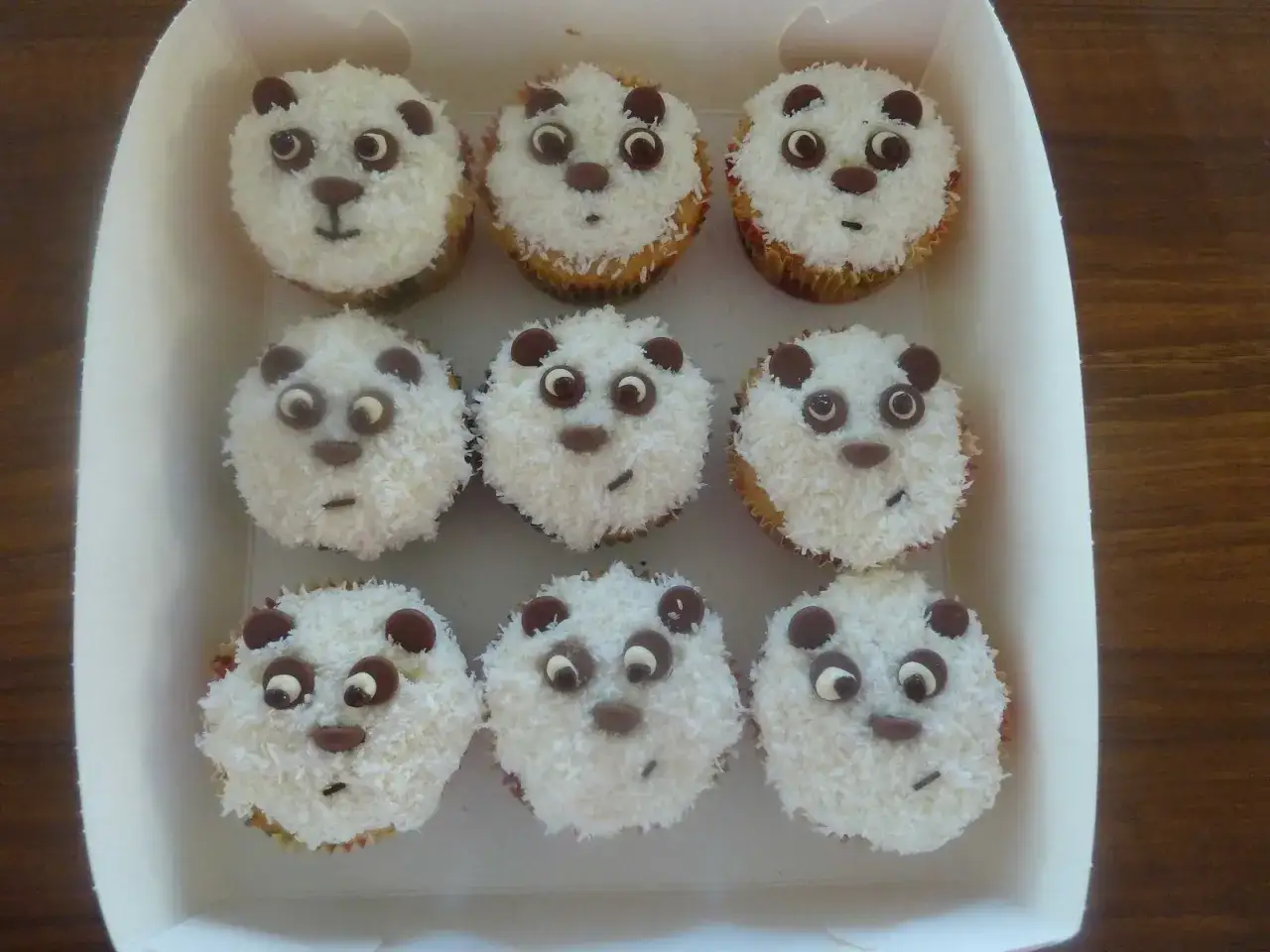 Nio gulliga pandacupcakes med kokosflingor och chokladdetaljer, perfekta att baka till ett kalas.