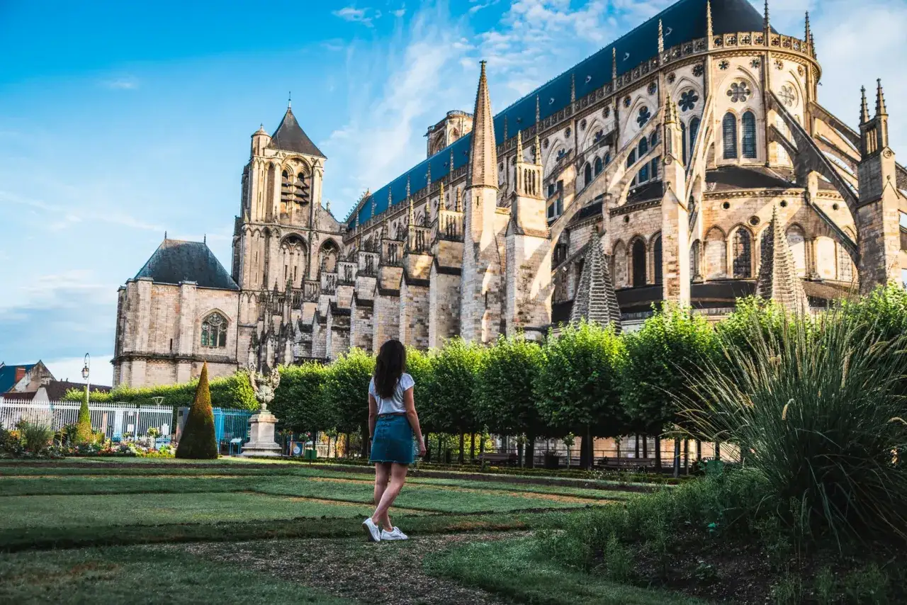 Une femme admire la majestueuse cath&eacute;drale de Bourges, un chef-d'&oelig;uvre gothique, rappelant l'opulence du **ch&acirc;teau Jacques C&oelig;ur** voisin.