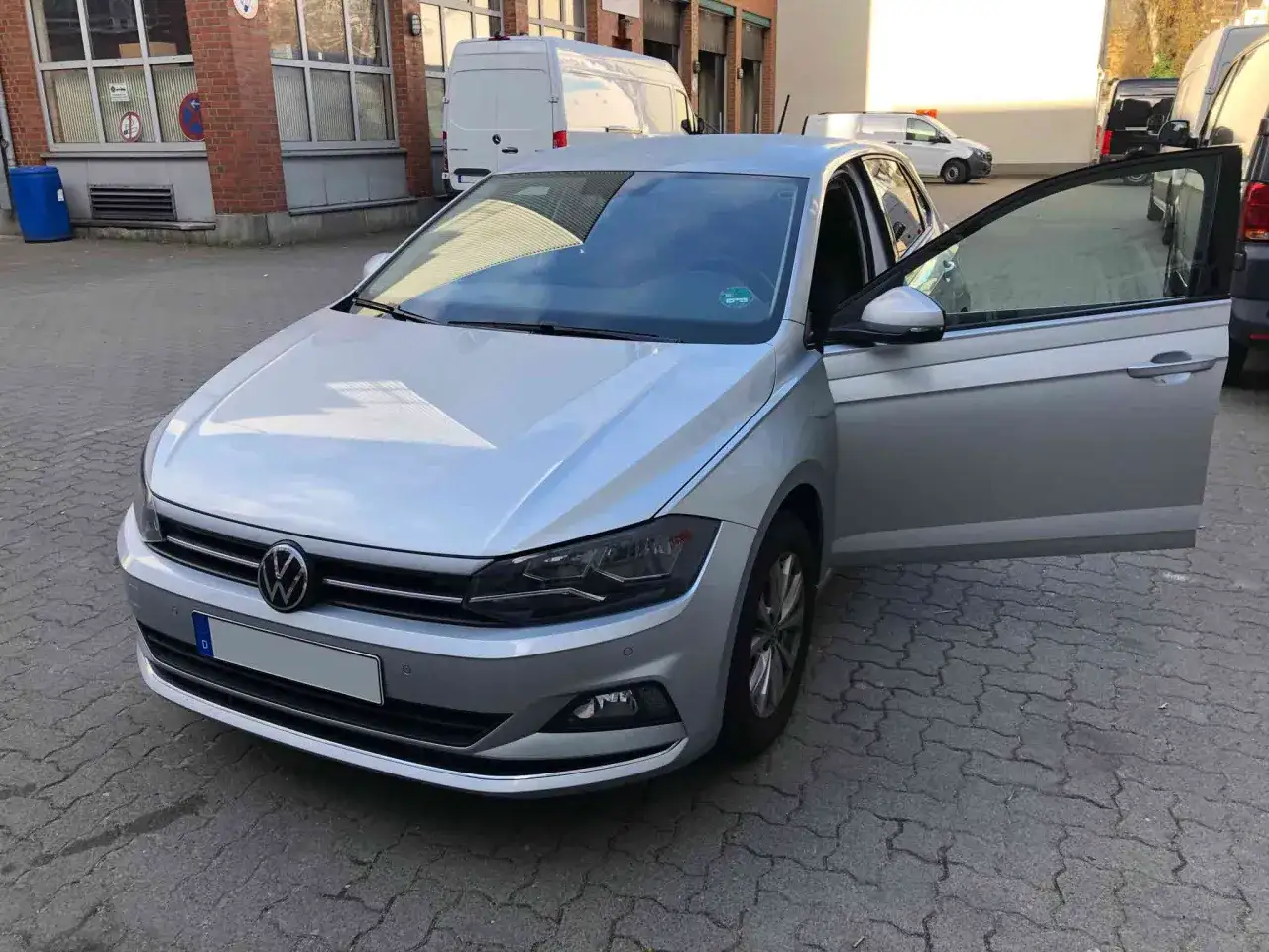 Silberner VW Polo 1.0 TSI 95 PS mit geöffneter Fahrertür. Mögliche Probleme mit dem Fahrzeug werden diskutiert.