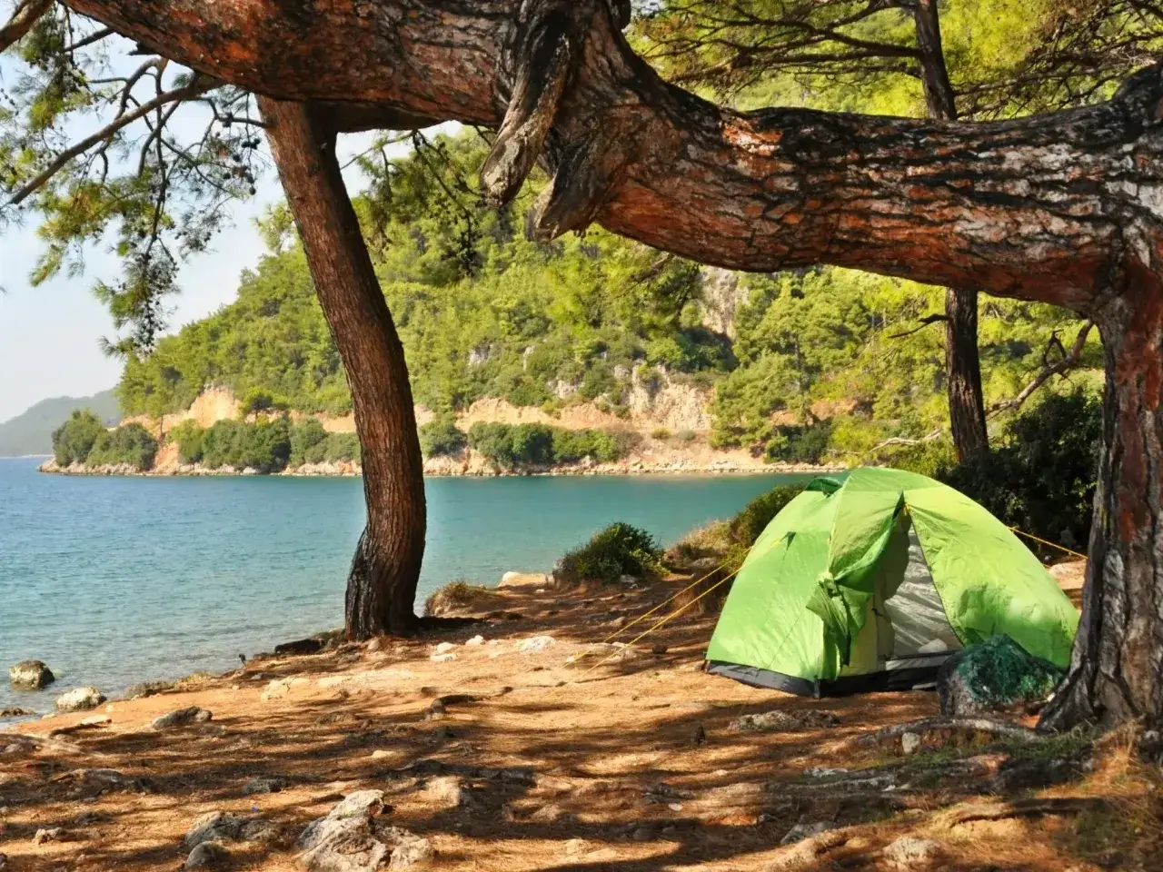 Zielony namiot na plaży, idealne miejsce na camping w Turcji. Woda, drzewa i spokój.