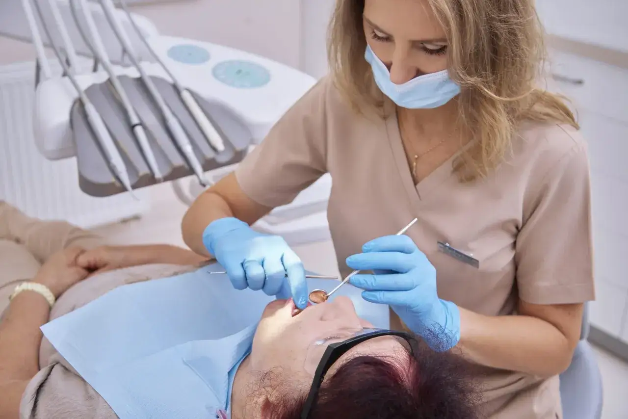 Dentystka bada dziąsła w ciąży, dbając o zdrowie przyszłej mamy.