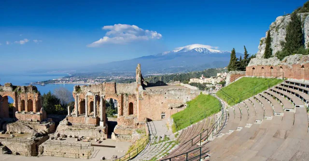 Antico teatro greco-romano a Taormina, Italia, con vista sull'Etna innevato e sul mare.